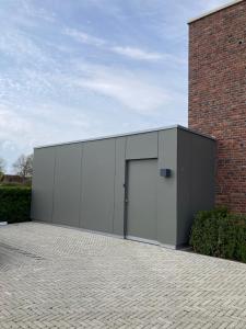 a large gray building with a door next to a brick building at Ferienwohnung Strandmuschel in Lembruch