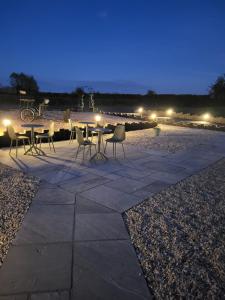 a patio with a table and chairs at night at The Old Barn in Hanbury