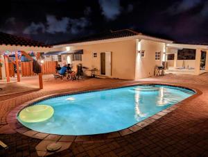 a swimming pool in front of a house at night at Ensuite Condo Aruba in Palm-Eagle Beach