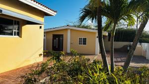 a yellow house with palm trees in front of it at Ensuite Condo Aruba in Palm-Eagle Beach