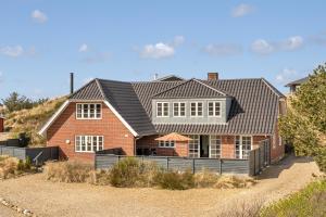 a red brick house with a black roof at Klithuset in Henne Strand