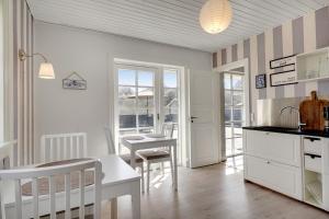 a kitchen with white cabinets and a table and chairs at Klithuset in Henne Strand
