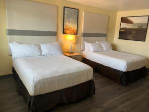 a hotel room with two beds and a lamp at Citrus Inn & Suites in Porterville