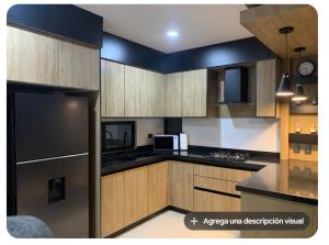 a kitchen with wooden cabinets and a black refrigerator at Complejo Las Flores departamento 3 in Durango