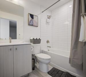 a white bathroom with a toilet and a bath tub at Open concept with city views in Kitchener +21 photos