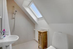 a bathroom with a sink and a toilet and a skylight at Klithuset in Henne Strand +28 photos
