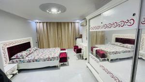 a bedroom with two beds and a mirror at Maison yassine in Douz