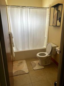 a bathroom with a white shower curtain and a toilet at Leemclean gated vacation home in Spanish Town