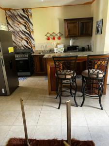a kitchen with two chairs and a table and a refrigerator at Leemclean gated vacation home in Spanish Town