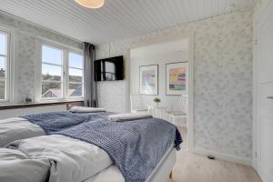 a white bedroom with a bed and a tv at Klithuset in Henne Strand