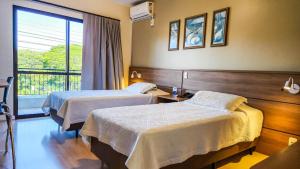 a hotel room with two beds and a window at Hotel Fiorio in Flores da Cunha