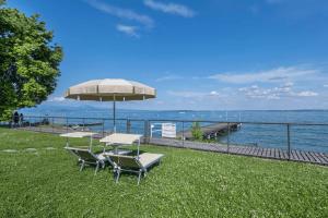 a group of tables and chairs under an umbrella at MGH- Lake Serenity Apartment in Padenghe sul Garda