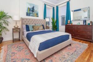 a bedroom with a bed and a dresser and blue curtains at Expansive Essential Triplex near T in Boston