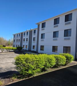 an apartment building with bushes in a parking lot at Austinburg Hotel in Austinburg