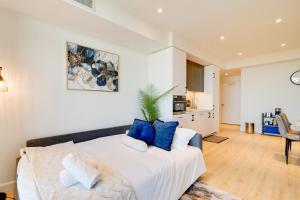 a bedroom with a large white bed with blue pillows at Modern Penthouse in Central KW in Kitchener