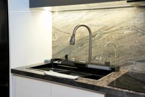 a kitchen sink with two faucets on a counter at Potka Apartments Tirane in Yzberishti +115 photos