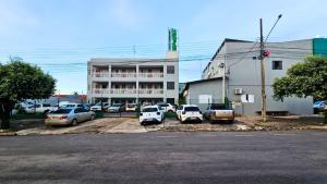 a parking lot with cars parked in front of a building at Hotel Colina Verde in Lucas do Rio Verde