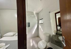 a bathroom with a toilet and a sink and a bed at Hotel Colina Verde in Lucas do Rio Verde