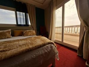 a bedroom with a bed and a large window at Apparthotel Le SALY Beach yenne in Toubab Dialaw