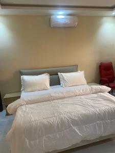 a large bed with white pillows and a red chair at Apparthotel Le SALY Beach yenne in Toubab Dialaw