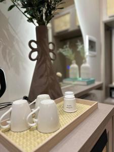 a tray with three coffee cups on a counter with a vase at Del Mare Rooms in Vlorë +45 photos