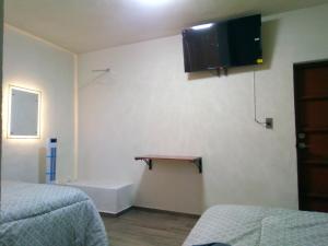 a room with two beds and a television on the wall at Callihotel in Tehuacán