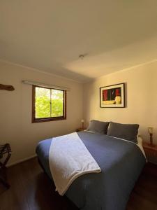 a bedroom with a blue bed with a window at Cabaña Castaño in Villarrica