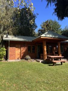 a log cabin with a picnic table in the yard at Cabaña Castaño in Villarrica