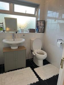 a bathroom with a toilet and a sink and a window at Spacious 3 bed semi-detached house in Luton