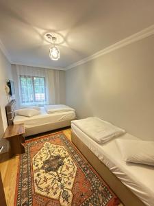 a bedroom with two beds and a rug at Çam Otel 2 in Uzungöl