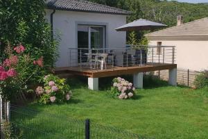 a house with a deck with a table and an umbrella at Entire house 6 guests Mountain view in Luri
