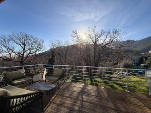 a deck with a couch and chairs on a balcony at Entire house 6 guests Mountain view in Luri