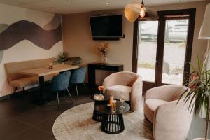 a living room with chairs and a table and a tv at Kyriad Quimper Sud in Quimper
