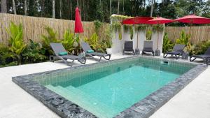a swimming pool with chairs and umbrellas in a backyard at Aranya Bliss Villa 102 in Wok Tum