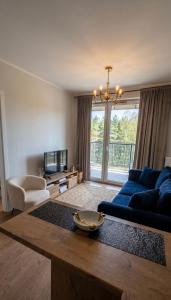 a living room with a blue couch and a tv at Apartament Wiosenna in Białystok