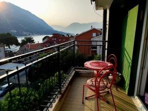 a red chair sitting on a balcony with a view at Sunshine Apartment in Dobrota