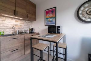 a kitchen with a table with stools and a microwave at Charmant studio climatisé à deux pas de la plage! in Anglet