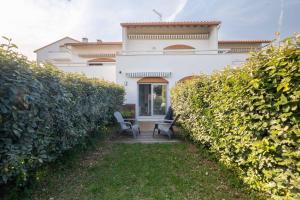 a white house with two chairs in front of a hedge at Charmant studio climatisé à deux pas de la plage! in Anglet