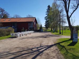 a row of white chairs on a dirt road in front of a barn at Billet Junior in Fredrikstad