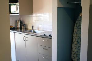 a kitchen with white cabinets and a sink at La Rochelle Motel in Akaroa +89 photos