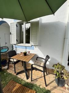 a wooden table and chairs with a green umbrella at Casa Gatu Verdi-Garden Apartment with Pool in Carvoeiro