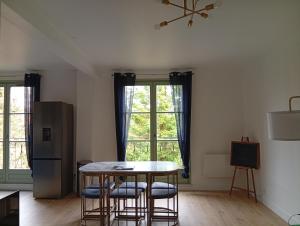 a kitchen with a table and chairs and a refrigerator at Le Green de Bellême in Bellême