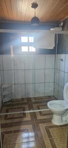a bathroom with a toilet and a wooden floor at Vale do Monte Verde Chalet in Camanducaia