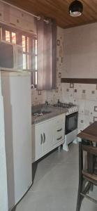 a kitchen with white cabinets and a stove top oven at Vale do Monte Verde Chalet in Camanducaia