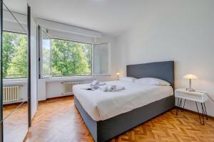 a bedroom with a large bed and two windows at Lido Apartment Locarno with Balcony and Parking - Happy Rentals in Locarno