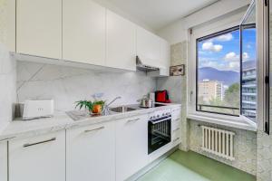 a white kitchen with a sink and a window at Lido Apartment Locarno with Balcony and Parking - Happy Rentals in Locarno