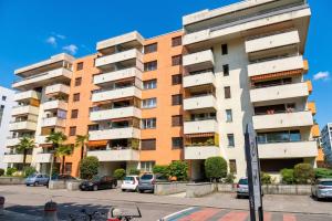 a tall apartment building with cars parked in a parking lot at Lido Apartment Locarno with Balcony and Parking - Happy Rentals in Locarno