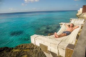a man laying on a hammock near the ocean at Hotel B Unique in Cozumel