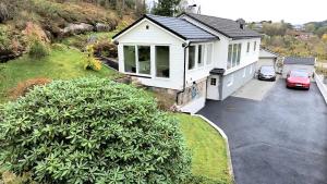 a white house with a car parked in a driveway at Fjordclaw SNM- adjoining the Bergen city & Nature, Free parking in Bergen
