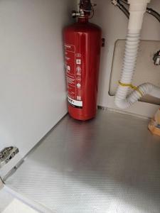 a red fire hydrant is sitting next to a wall at Myrteni studio II in Nea Peramos